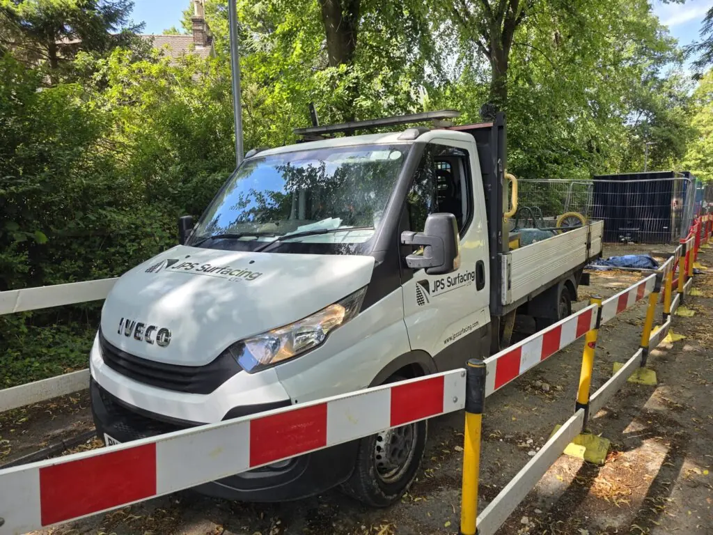 JPS Surfacing flatbed parked on a live site behind barriers and fencing